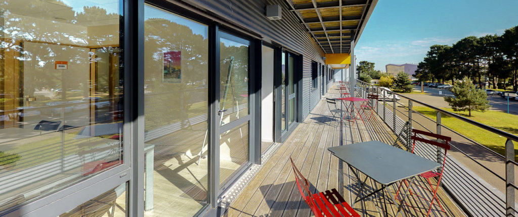 Vue terrasse table chaise pelouse nature arbres soleil mer bureaux centre d'affaires Lorient mer